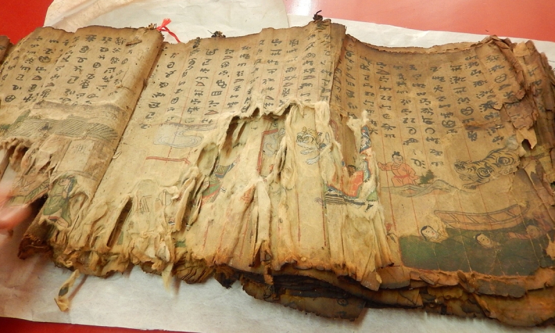 یانگ لیکون (جلو) یک نسخه خطی باستانی را همانطور که شاگردانش مشاهده می کنند بازیابی می کند. عکس:  از کتابخانه استانی یوننان
